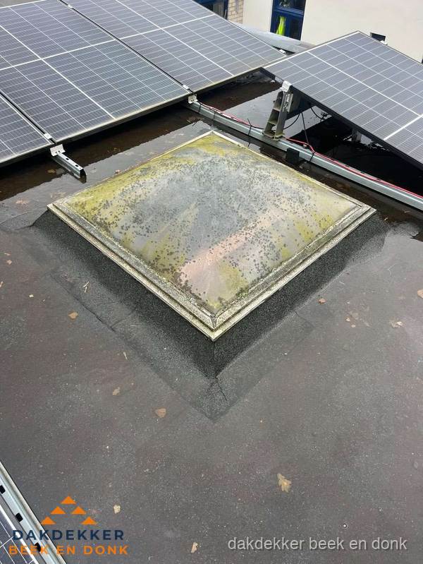 Vervuilde lichtkoepel op plat dak met zonnepanelen in Beek en Donk