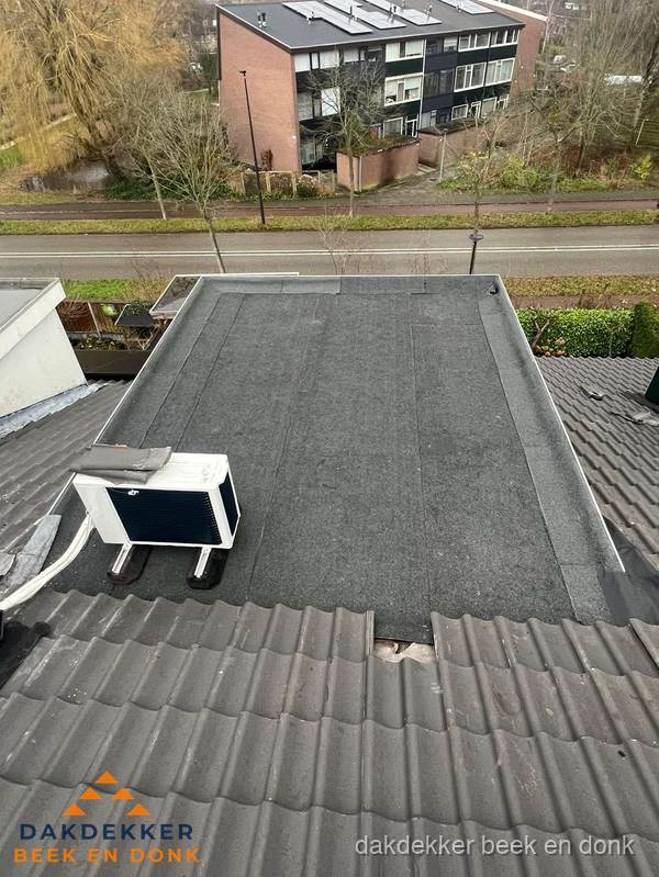Plat dak inspectie met bitumen bedekking naast schuin pannendak in Beek en Donk