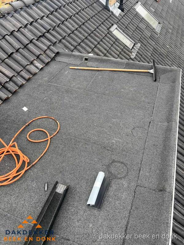 Plat dak reparatie met gereedschap en loodstroken in Beek en Donk
